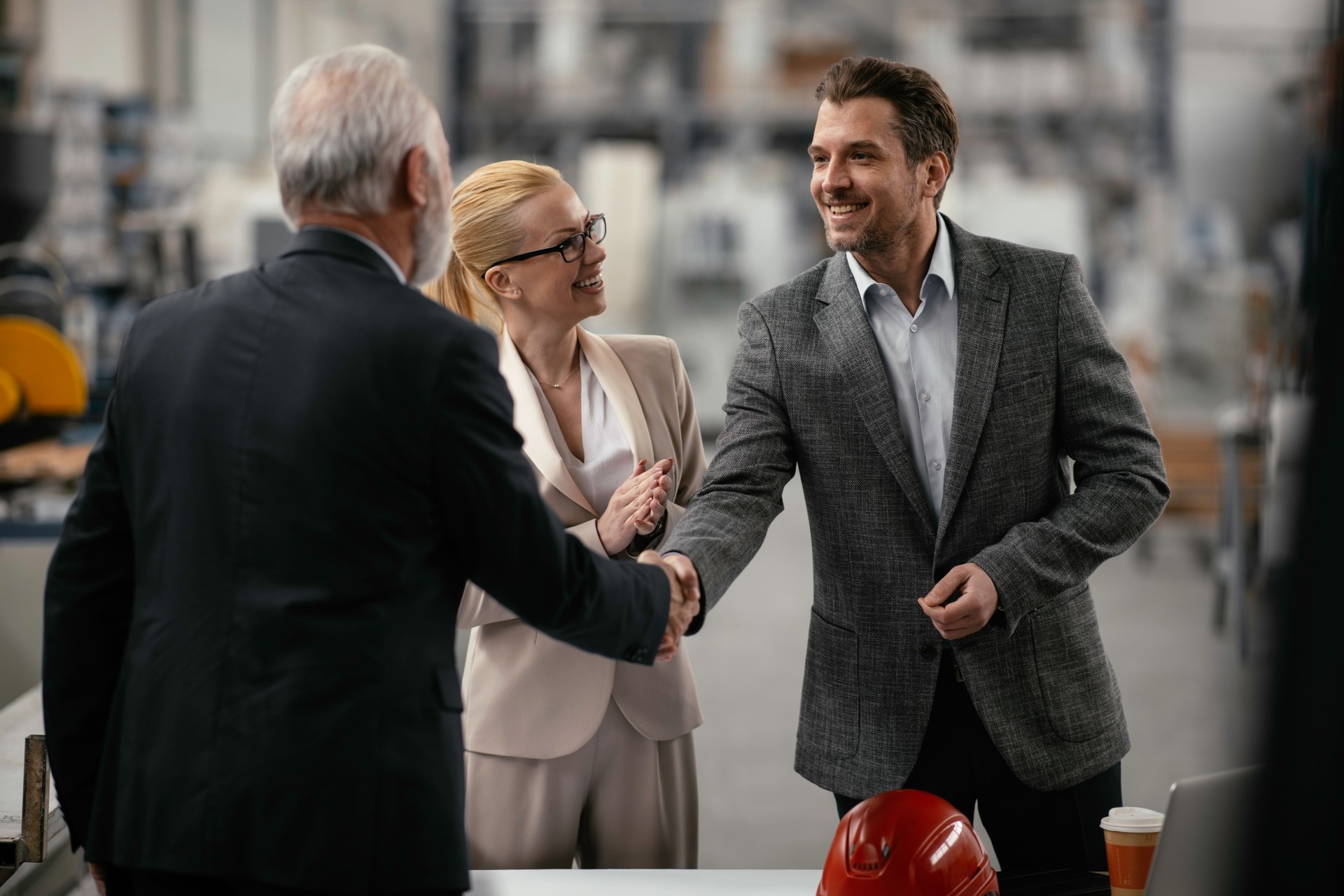 Colleagues handshake in factory.